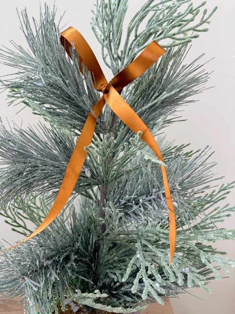 Frosted pine branch with an orange ribbon on a light background
