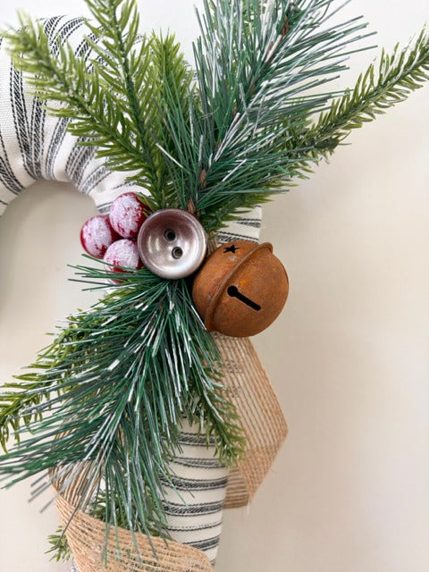 Decorative  greenery, berries, and a bell on a neutral background