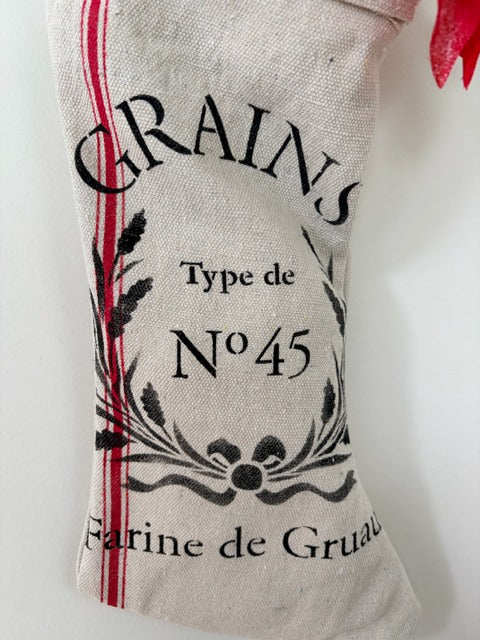 Textured fabric stocking with 'Grains' and 'Farine de Gruau' print on a white background