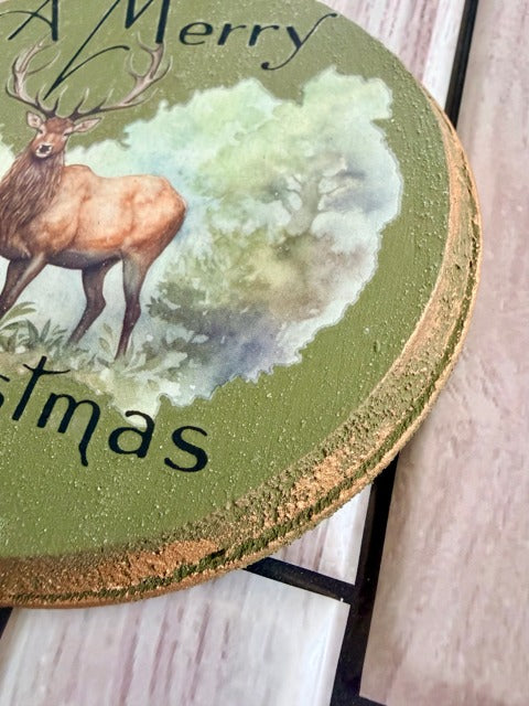 Round green ornament with a deer illustration and 'Merry Christmas' text 