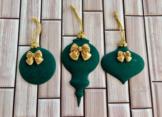 Three green Christmas ornaments with gold bows 