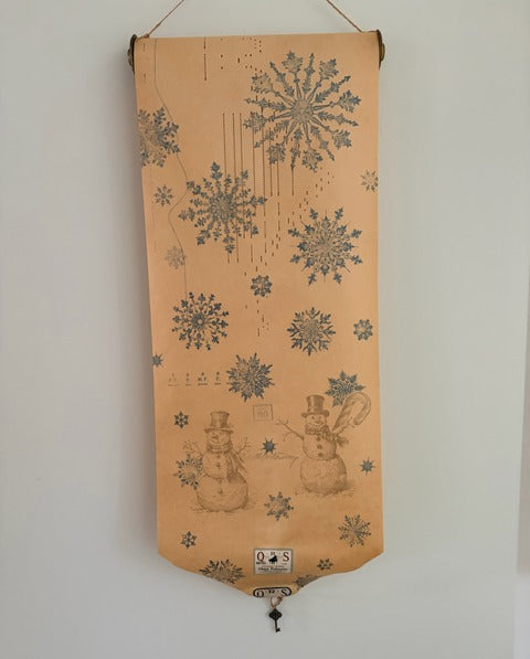 Decorative banner with snowflake and snowman designs hanging on a wall.