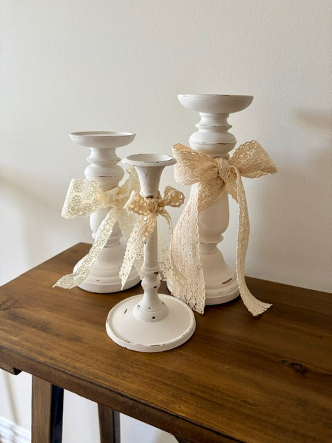 White candlestick trio with lace bows.