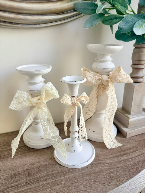 White candlestick trio with lace bows.