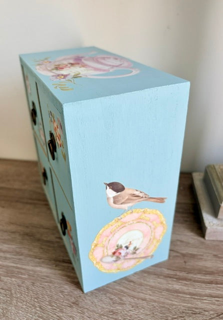 Side view of tea chest with bird on tea saucer image.
