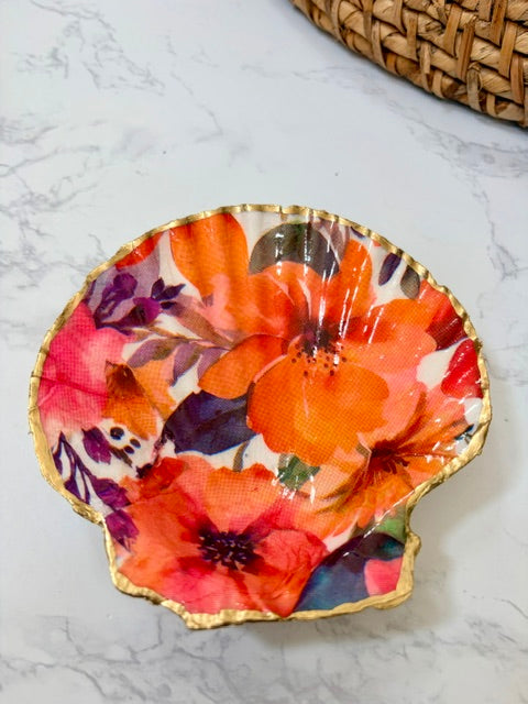 A small decorative dish with an irregular scalloped edge, featuring a floral  pattern on a white background with a gold-toned distressed rim.