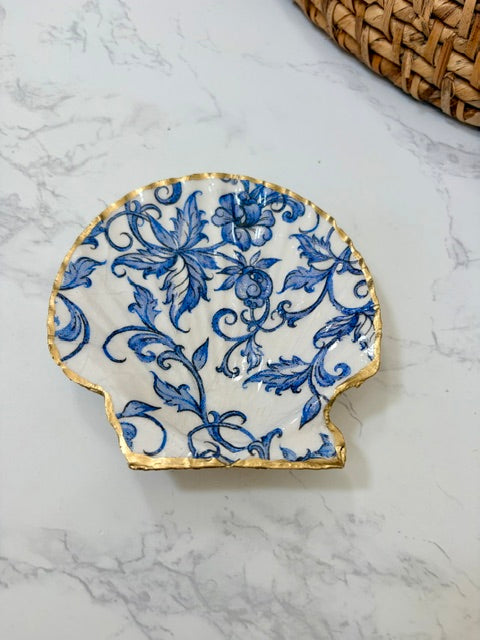 A small decorative dish with an irregular scalloped edge, featuring a floral  pattern on a white background with a gold-toned distressed rim.