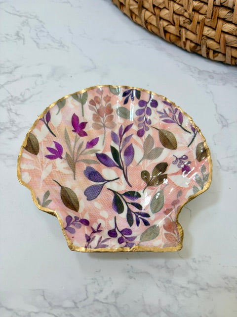 A small decorative dish with an irregular scalloped edge, featuring a pink floral pattern on a white background with a gold-toned distressed rim.