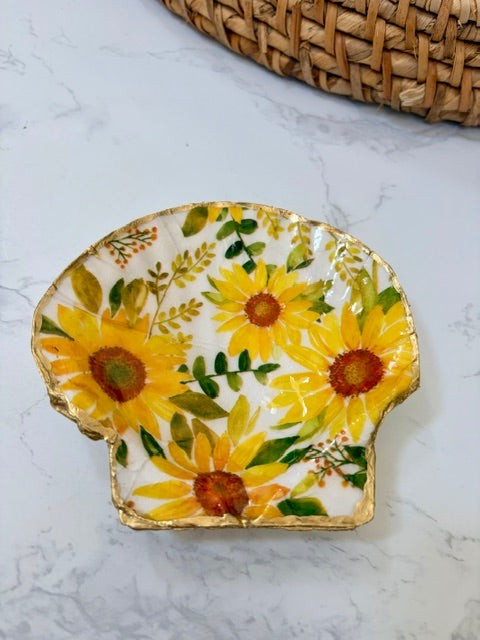 A small decorative dish with an irregular scalloped edge, featuring a floral  pattern on a white background with a gold-toned distressed rim.