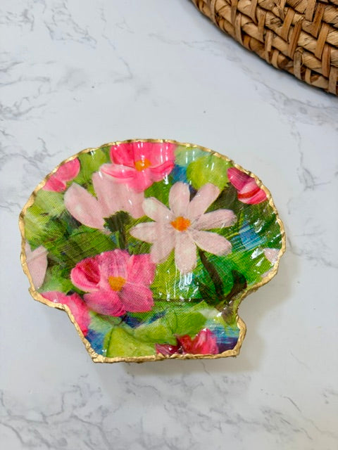 A small decorative dish with an irregular scalloped edge, featuring a  floral pattern on a green background with a gold-toned distressed rim.