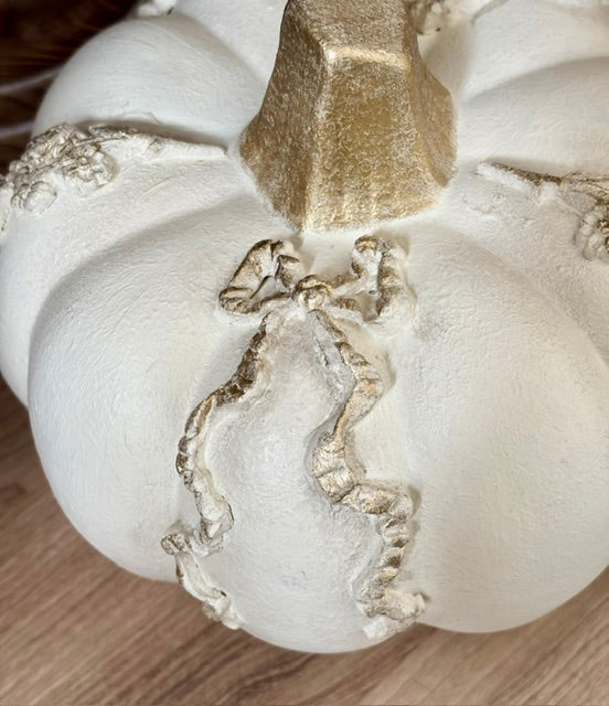 Close up of white pumpkin with a gold bow motif.