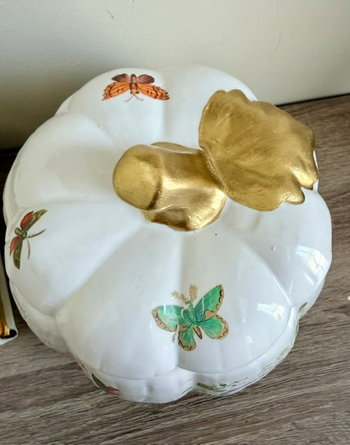 Lid of a white ceramic pumpkin with gold stem.