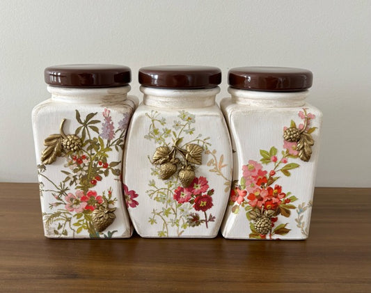 Three decorative ceramic jars with floral patterns on a wooden surface.