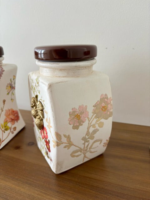 Decorative jar with floral design and brown lid on a wooden surface