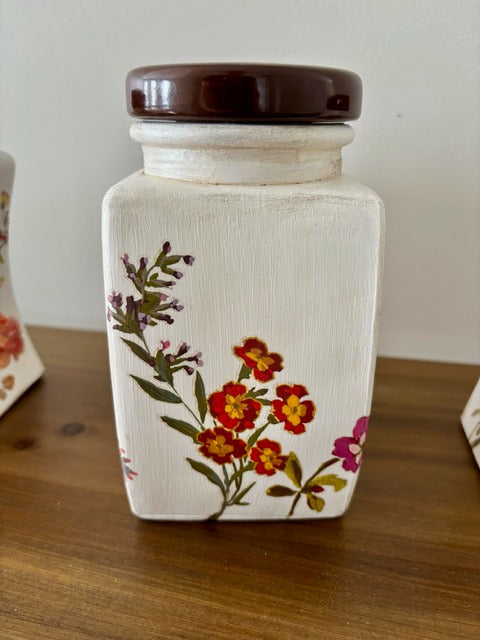 Decorative ceramic jar with floral design and brown lid on a wooden surface