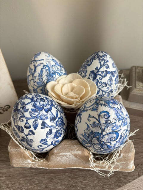 Decorative eggs with blue floral patterns in an egg carton
