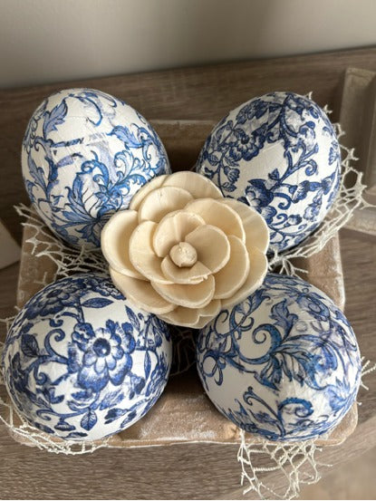 Decorative eggs with blue floral patterns in an egg carton