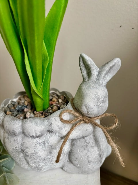 White tulips in a decorative pot with a small rabbit figure 