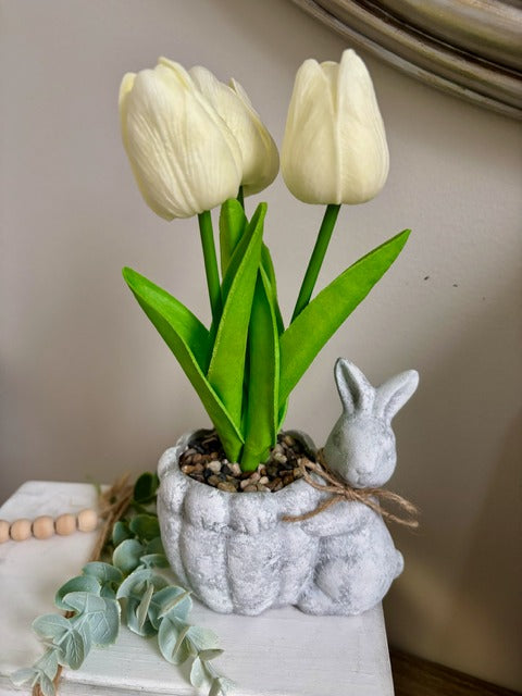 White tulips in a decorative pot with a small rabbit figure 