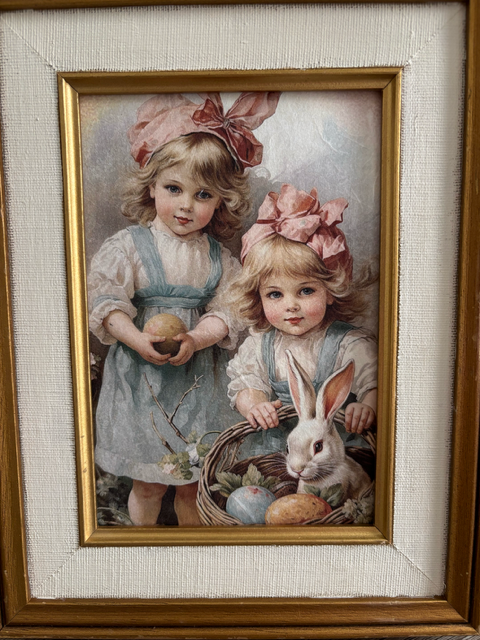 Framed artwork of two children with a rabbit on a white surface.