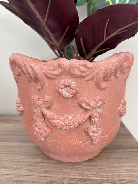 Decorative terracotta pot with floral designs on a wooden surface