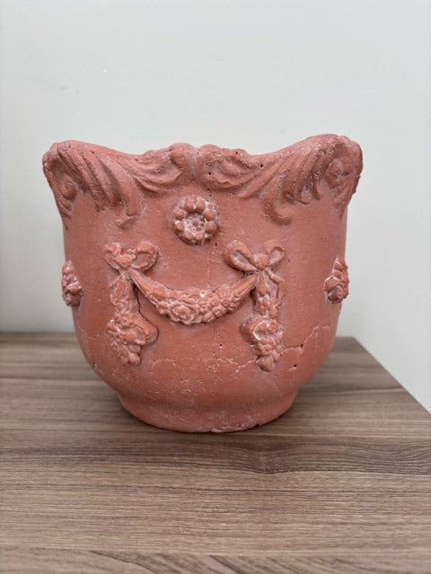 Decorative terracotta pot with intricate designs on a wooden surface.