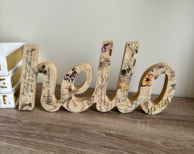 Decorative wooden letters spelling 'hello' on a wooden surface with a neutral background