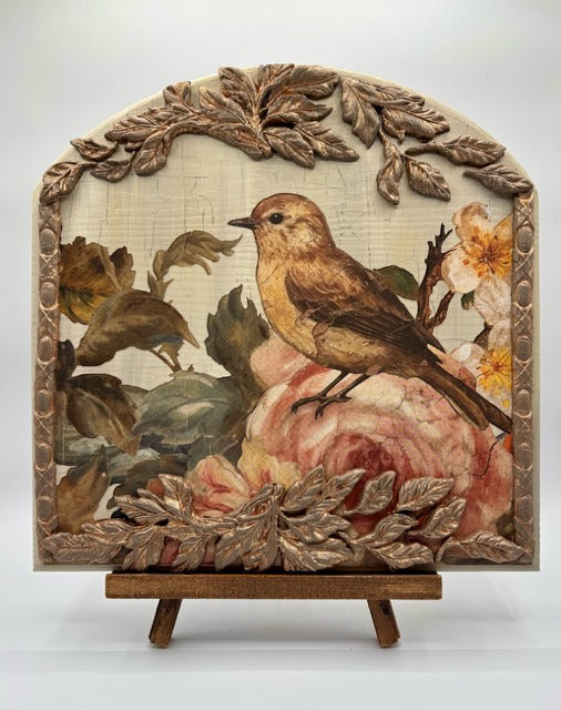 Decorative piece with birds and flowers on a stand against a white background
