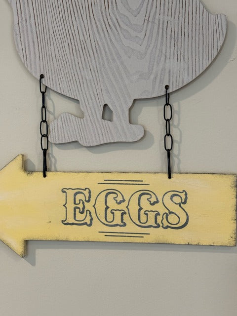 Decorative sign with a chicken silhouette and 'EGGS' text on a wooden arrow