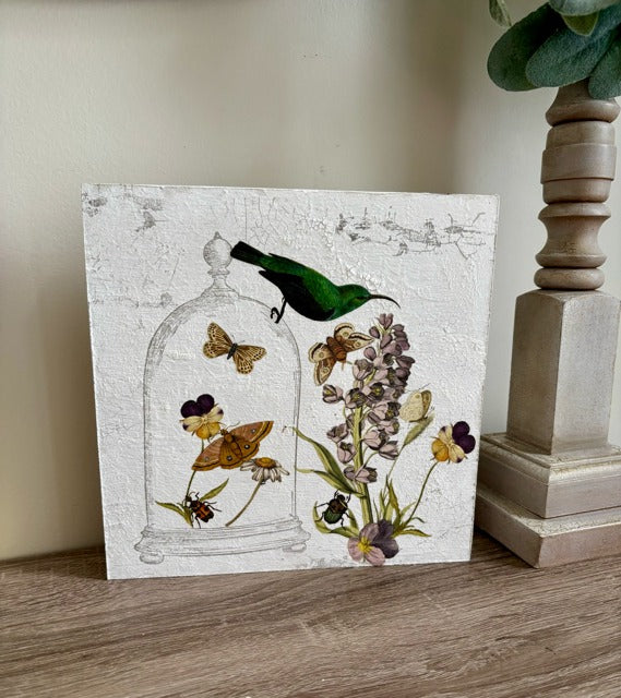 Decorative wood panel with butterflies, flowers, and a bird on a white, textured background