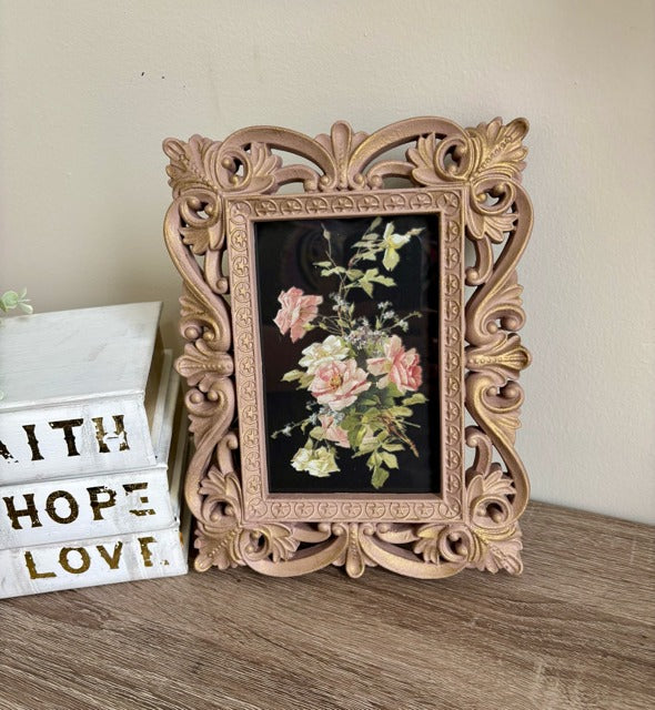 Decorative ornate frame with floral painting on a wooden surface