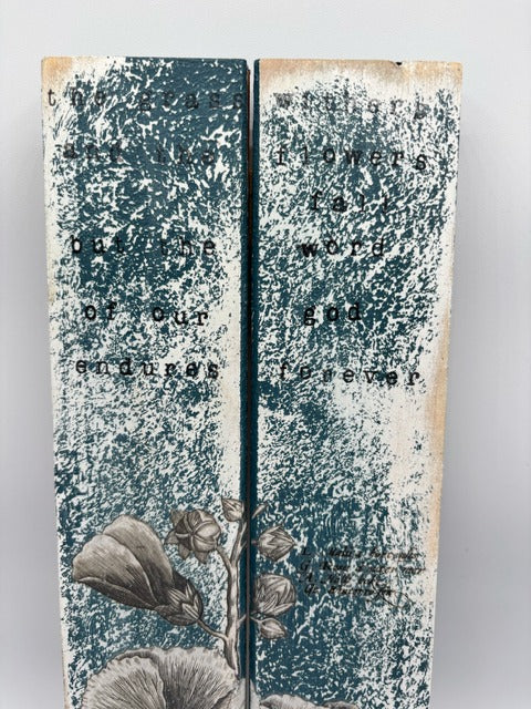 Wood plaque with text and floral elements on a textured surface