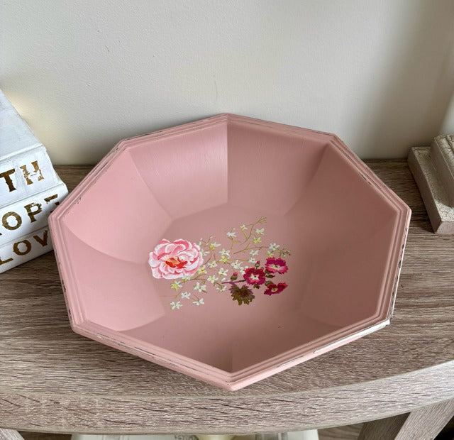 Pink decorative bowl with floral design on a wooden surface
