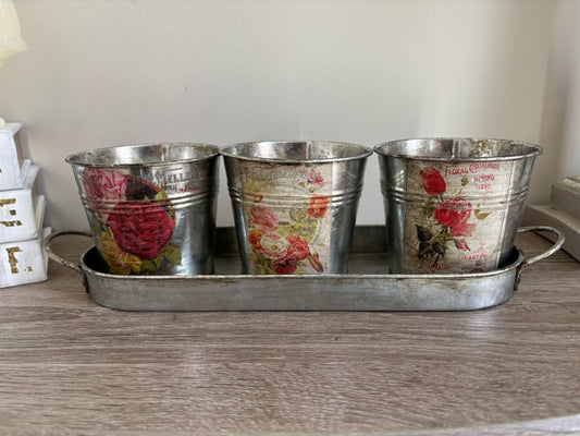 Three metal buckets with floral decal on a tray