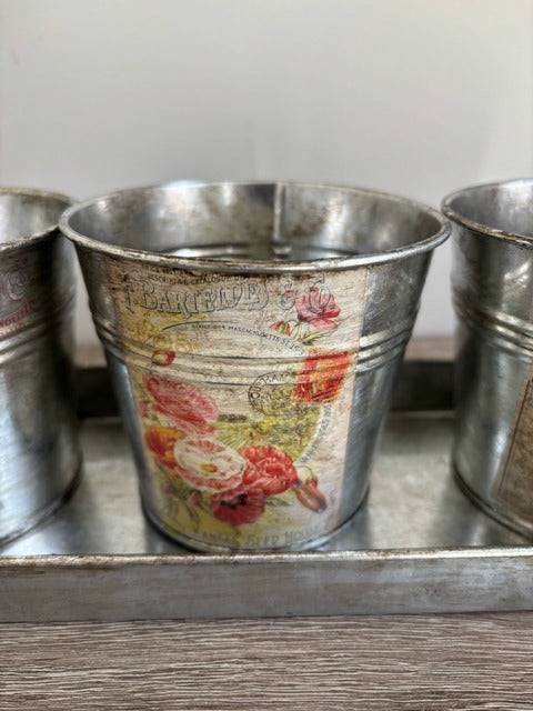 Three metal buckets with floral decal on a tray