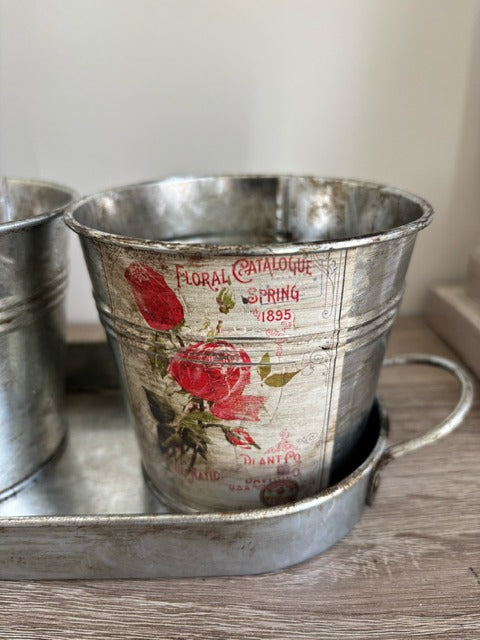 Three metal buckets with floral decal on a tray
