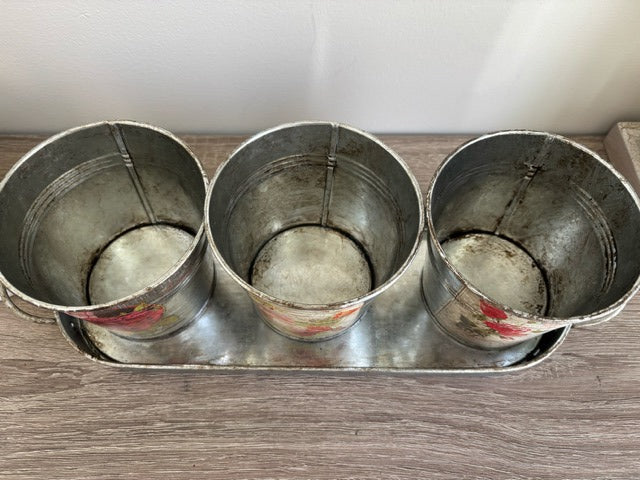 Three metal buckets with floral decal on a tray