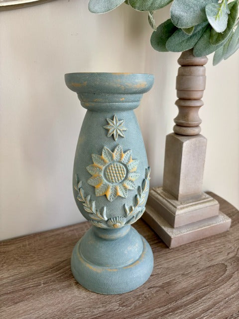 Decorative blue candle holder with floral design on a wooden surface