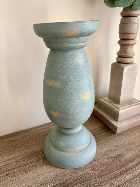 Decorative blue candle holder with yellow accents on a wooden surface