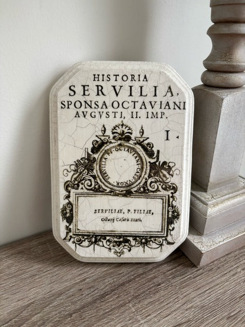 Decorative plaque with classical text and design on a wooden surface