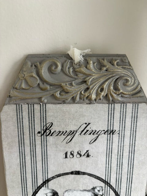 Decorative wall piece with intricate design and text on a plain background
