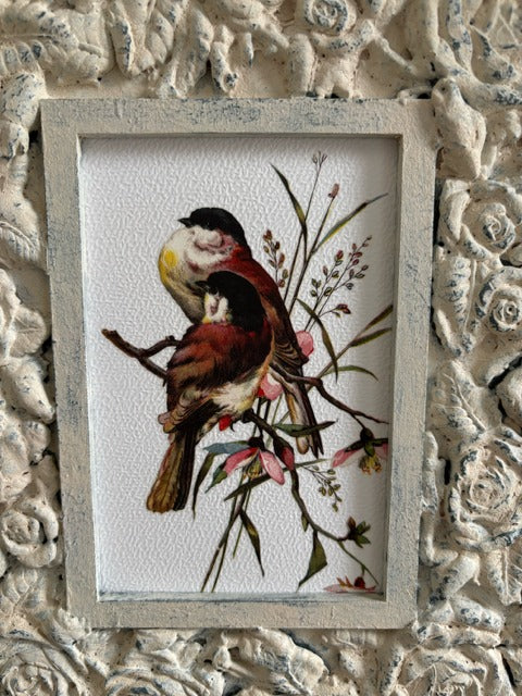 Decorative frame with floral patterns holding a print of a bird on a branch.