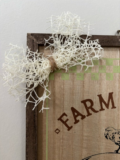 Decorative sign with 'Farm' text and white decorative elements on a plain background
