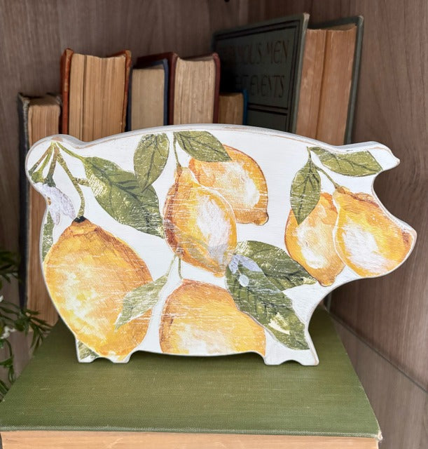 Decorative pig-shaped figurine with lemon design on a green surface.