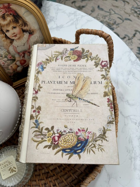 Decorative book with floral and botanical design on a wicker tray