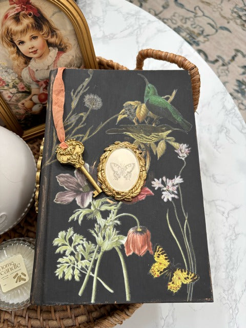 Decorative book with floral and bird design on a textured surface