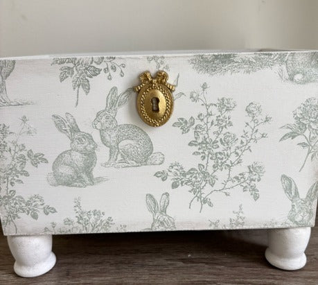 Decorative box with rabbit design and gold keyhole.