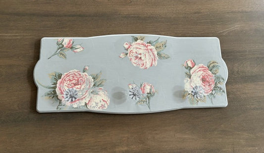 Decorative wall hanger with floral designs on a wooden surface