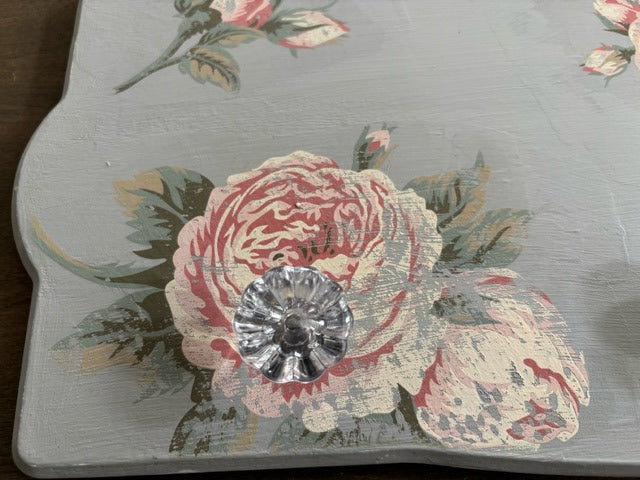 Decorative knob with floral design and a central crystal on a gray background