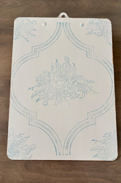 Decorative clipboard with floral design on a wooden surface
